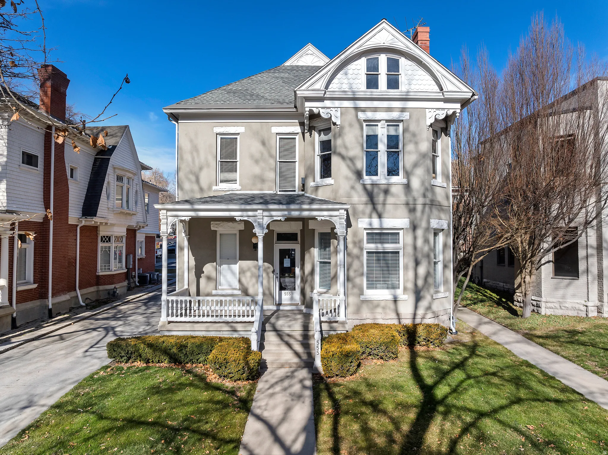 Historic architectural facade featuring a covered porch with intricate detailing, symmetrical window placement, and a prominent arched pediment