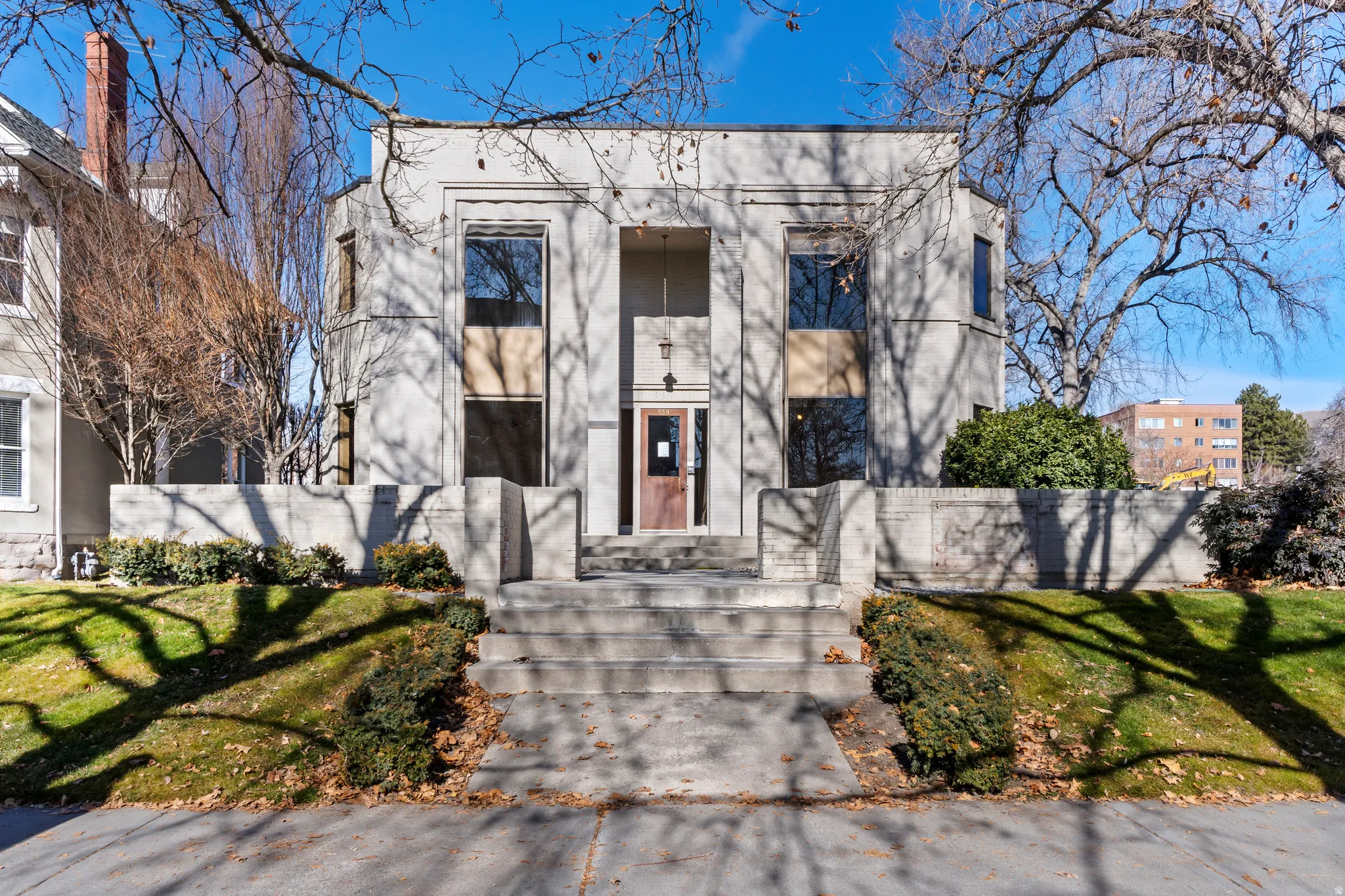 Stately concrete-block facade featuring a prominent central entrance, tall multi-pane windows, and a raised concrete staircase