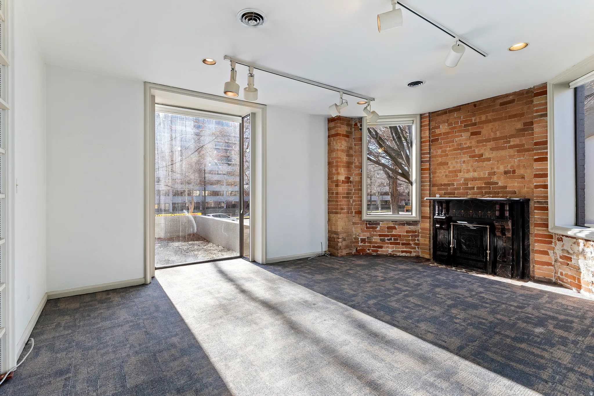Exposed brick accent wall with a black cast iron fireplace, complemented by modular carpet flooring