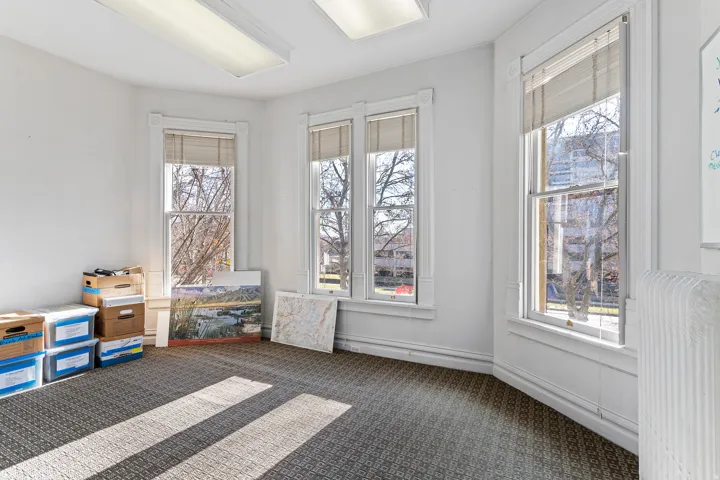 Room featuring multiple windows with traditional trim, carpeted flooring, and overhead fluorescent lighting