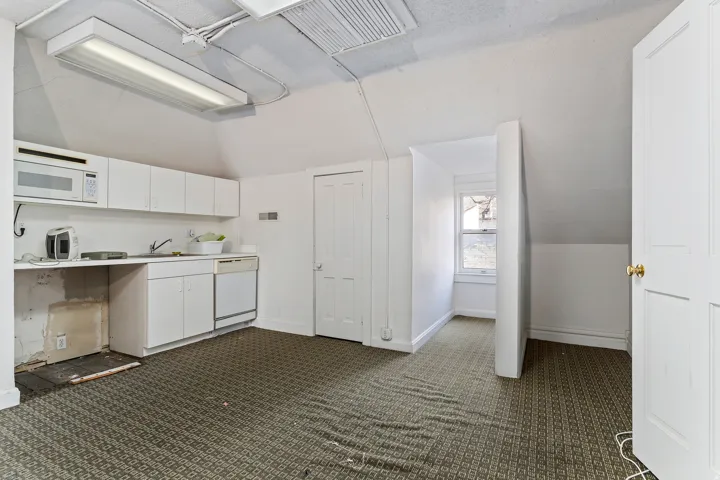 Kitchenette featuring white cabinetry, a built-in microwave, a sink, and a dishwasher