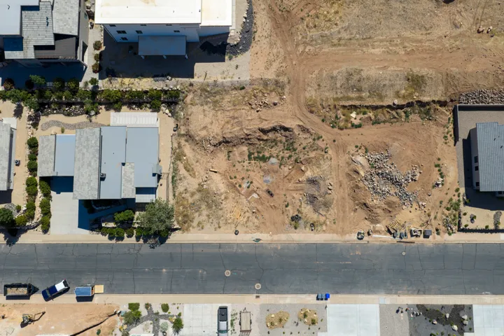 Expansive lot featuring undeveloped terrain and street frontage, flanked by established properties