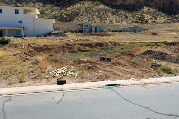 Cleared lot with graded earth, existing curb, and asphalt street frontage