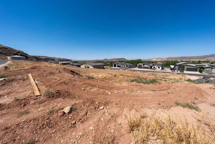 Expansive undeveloped land featuring a clear blue sky overhead and distant residential structures