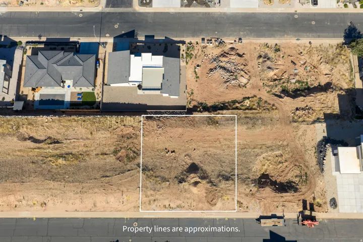 Expansive vacant lot featuring an approximation of property boundaries, surrounded by existing residential structures and undeveloped land