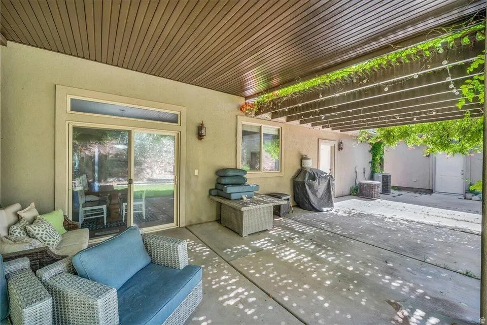 Expansive concrete patio area with a slatted wood pergola