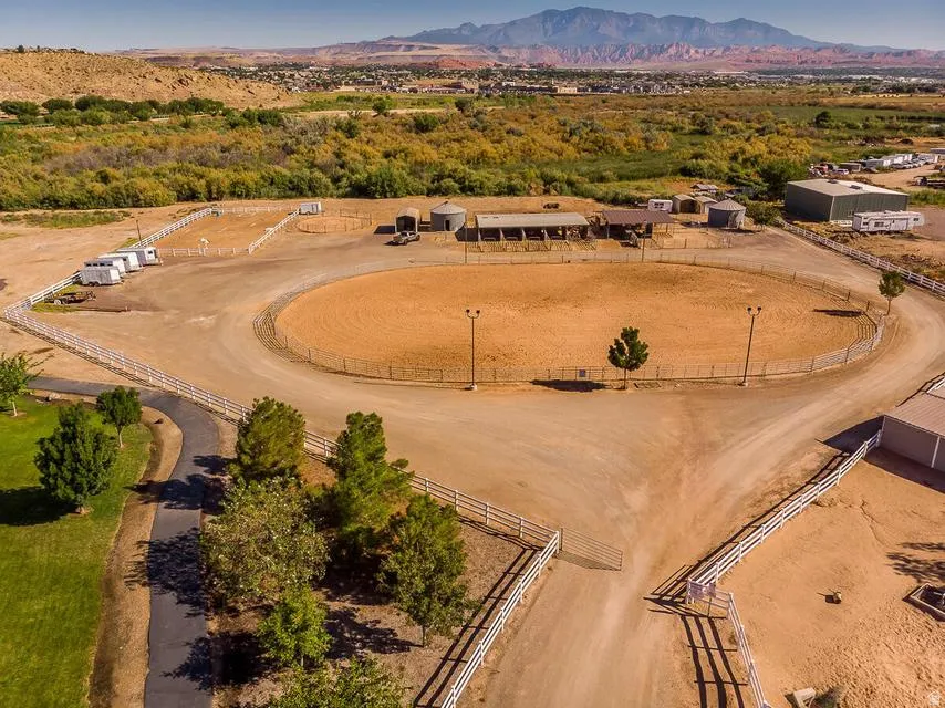 Expansive equestrian facility featuring a large riding arena, multiple fenced paddocks, and a stable building
