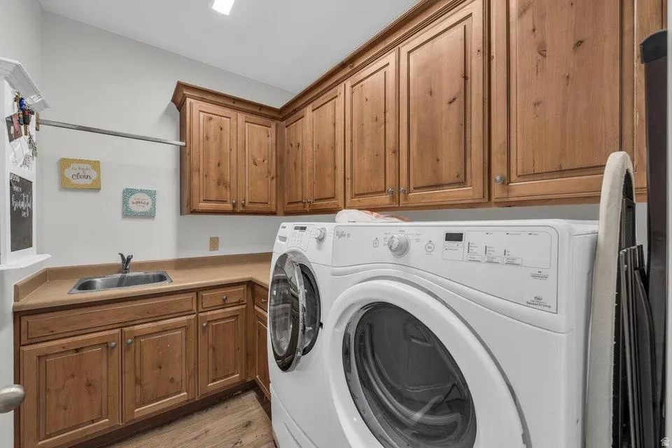 Dedicated laundry space featuring wood-finish cabinetry, a utility sink, and a clothes hanging rod