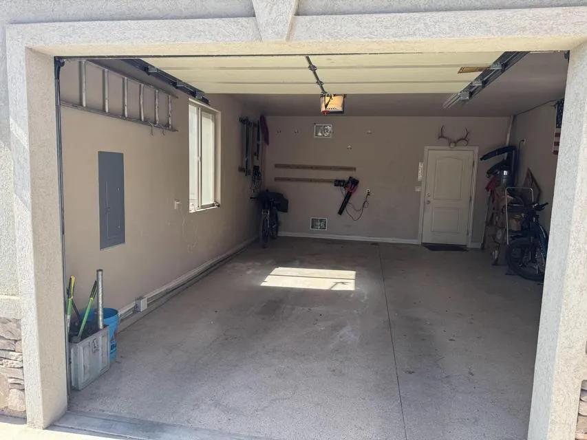 Attached two-car garage featuring a concrete floor, painted interior walls, and a side window