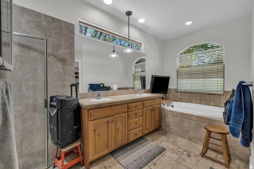 Bathroom featuring a dual-sink vanity with light wood cabinetry and a neutral countertop