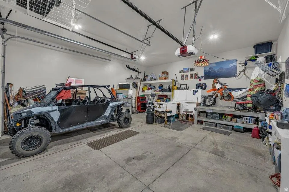 Spacious garage featuring a concrete floor, overhead storage racks, garage door opener mechanisms, and recessed ceiling lighting