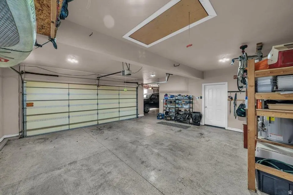 Spacious garage featuring a concrete floor, overhead lighting, and an overhead garage door