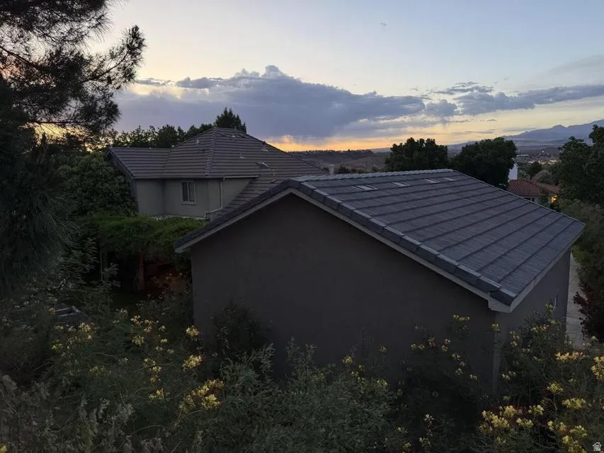 Tile roof on a neutral-toned stucco structure, featuring skylights and surrounded by established greenery