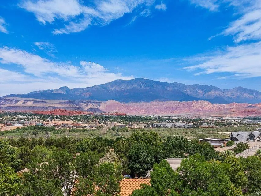 Expansive panoramic scenery featuring distant mountains, red rock formations, and a verdant landscape