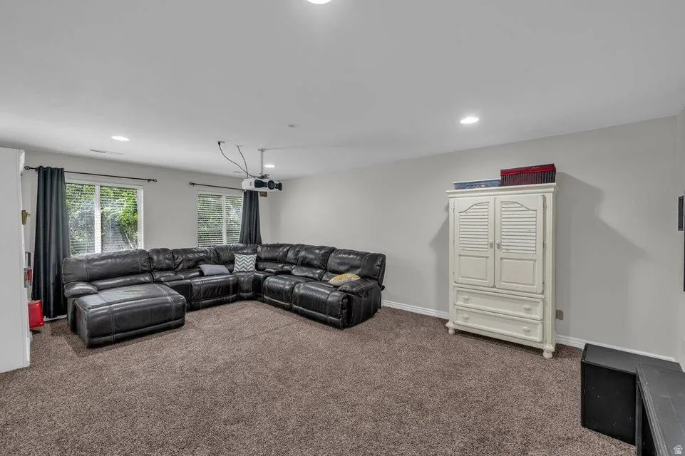 Spacious room with recessed lighting, two windows, and dark textured carpeting