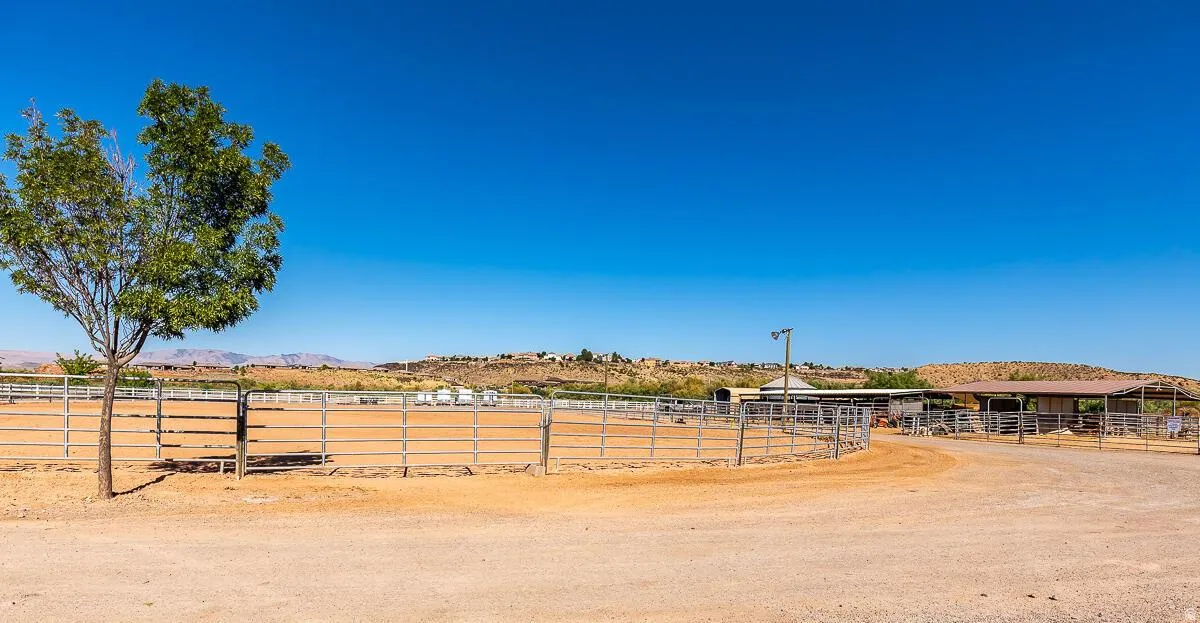Expansive equestrian facility featuring multiple fenced pens, a large open riding arena, and substantial covered structures