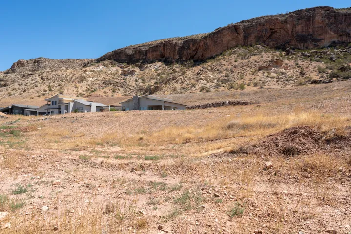 Modern residential structures situated at the base of a significant rock formation