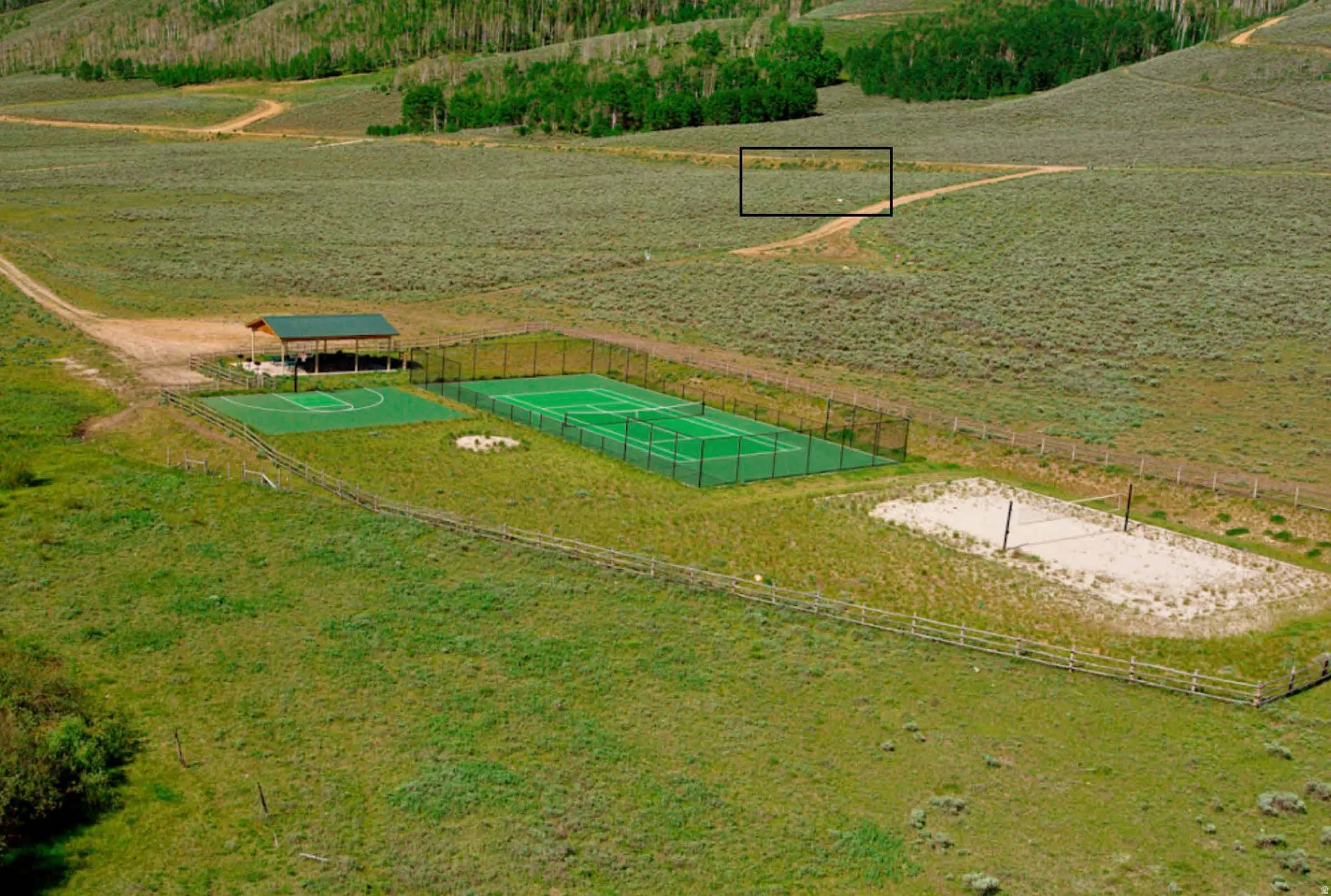 Multi-sport complex featuring a fenced tennis court, a basketball half-court, and a sand volleyball court