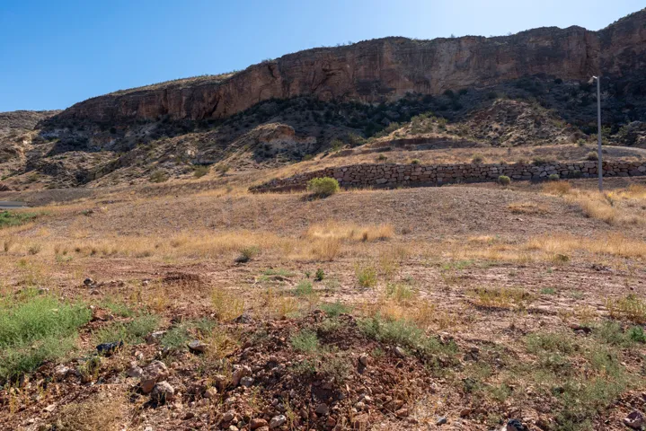 Expansive desert landscape with a prominent rock cliff formation and natural terrain