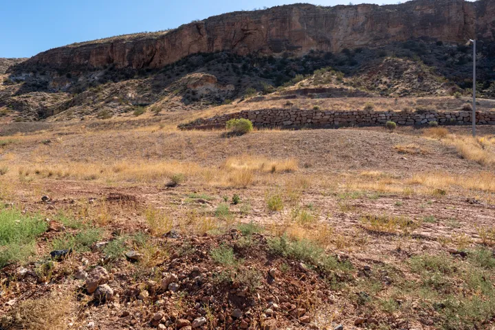 Terraced hillside lot with natural rock wall, expansive terrain, and distant rugged mountain backdrop