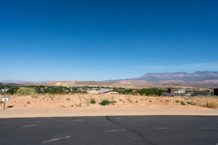Expansive lot featuring a paved street frontage, concrete sidewalk, and arid landscaping