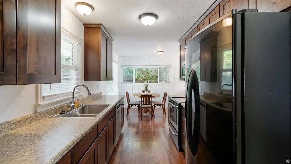 Galley kitchen featuring newer dark wood cabinetry, light-toned countertops, and stainless steel appliances