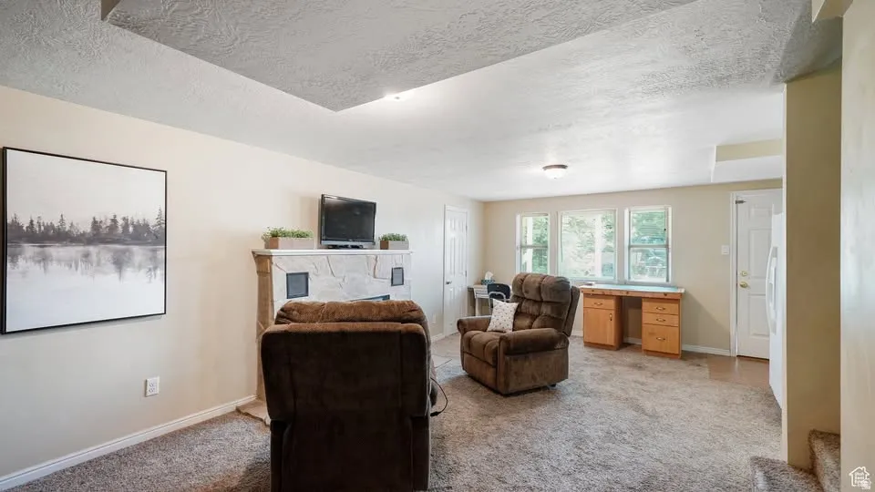 Spacious living area featuring a light stone fireplace and multiple windows