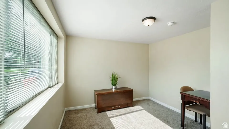 Master bedroom featuring a wide window with blinds, neutral-toned walls, and carpet flooring