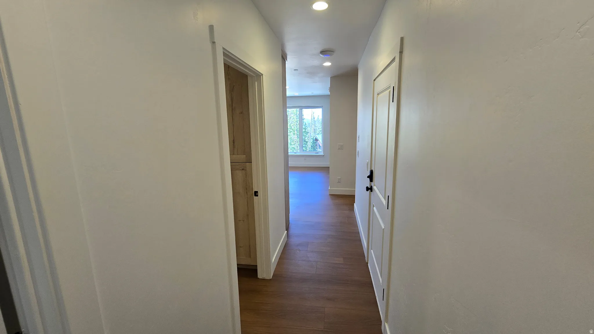 Hallway with wood-finish flooring, white walls, and recessed lighting
