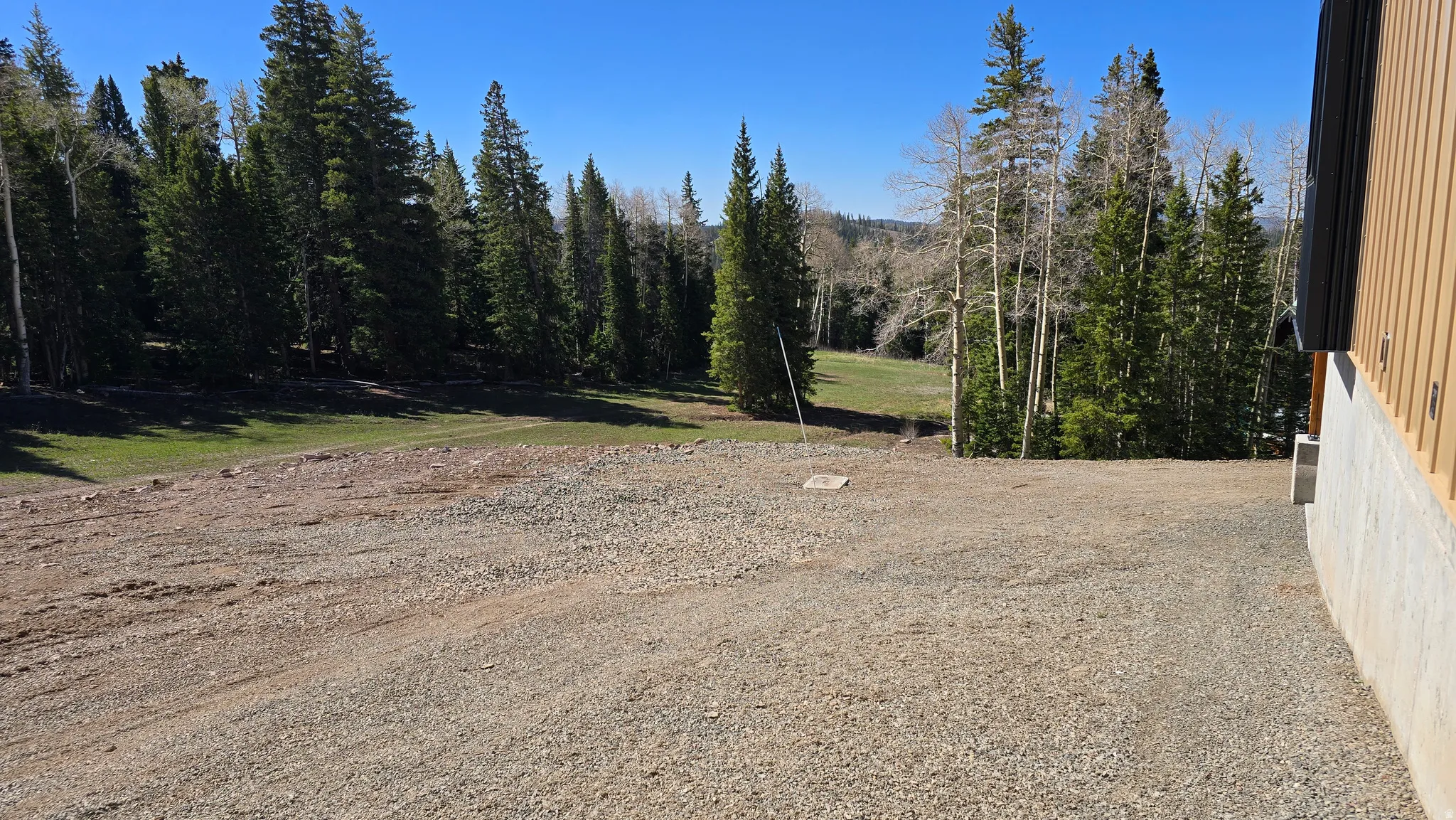 Gravel ground surface with a partial wood-paneled exterior and a concrete foundation
