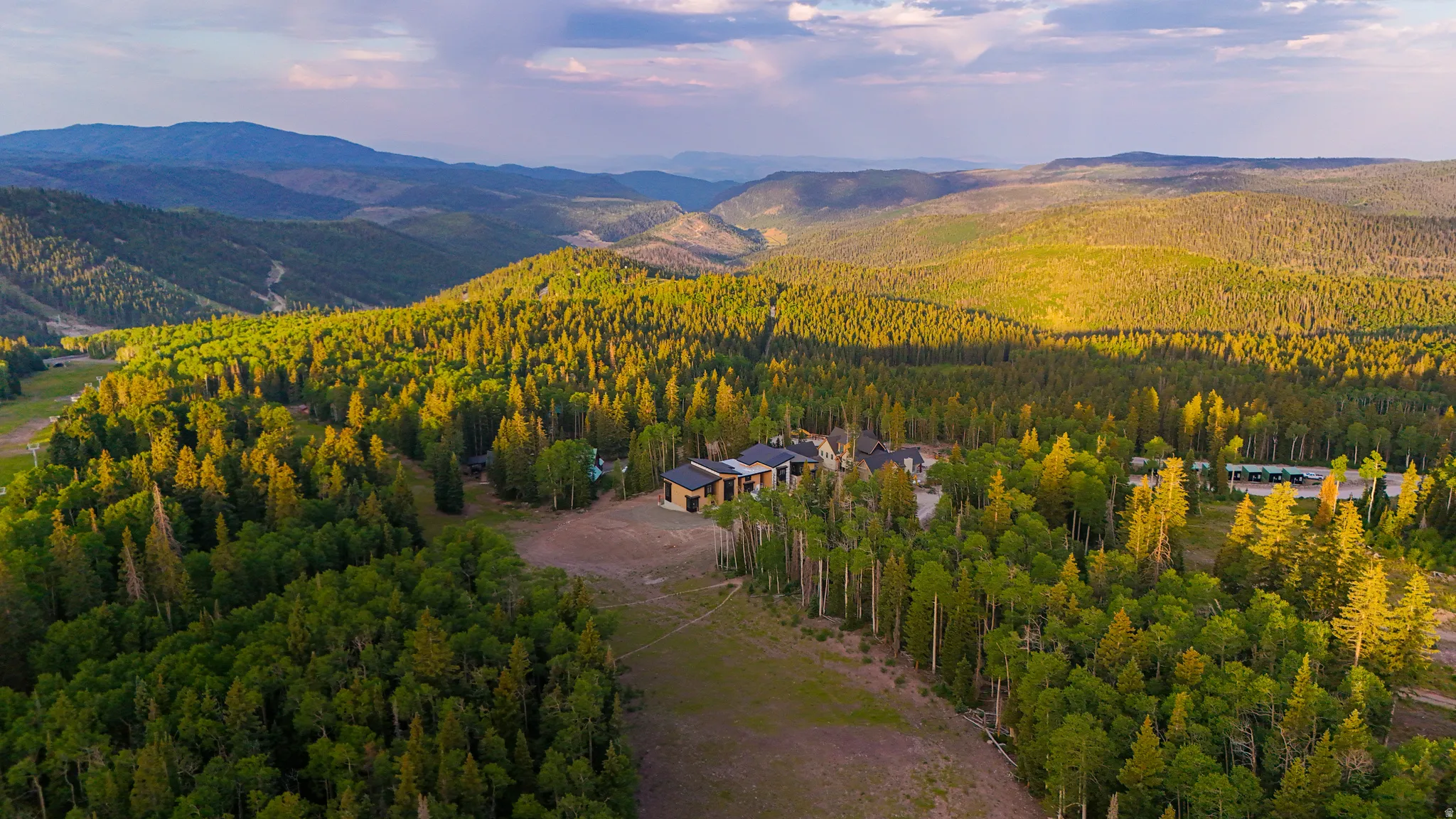 Extensive mountainous terrain surrounds a multi-structure property
