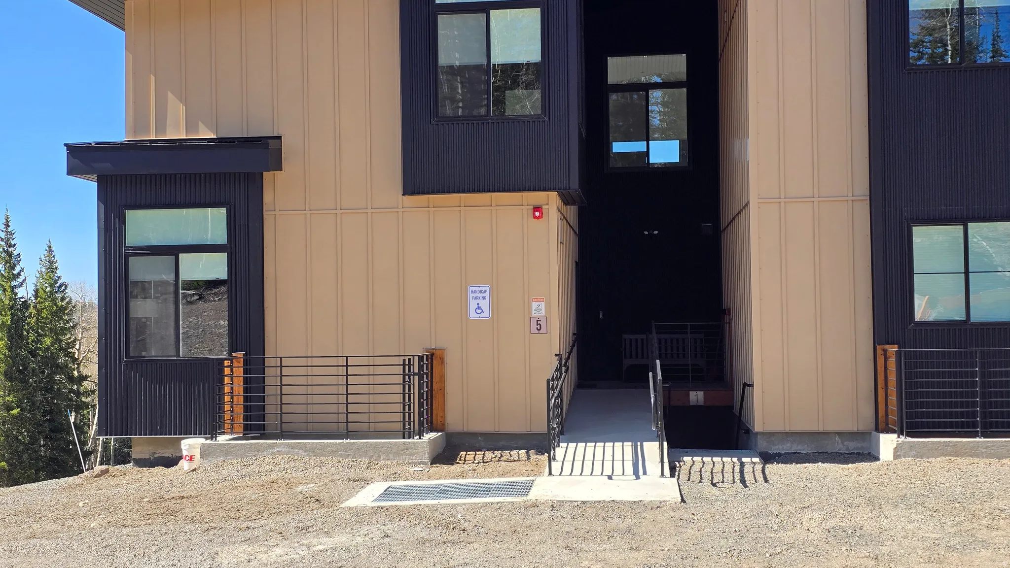 Modern multi-story building exterior featuring vertical panel siding in contrasting tan and dark tones