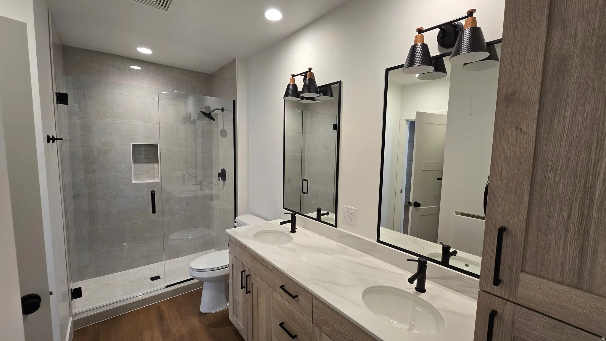 Modern bathroom featuring a dual vanity with white countertops and undermount sinks, black framed mirrors, and black sconce lighting