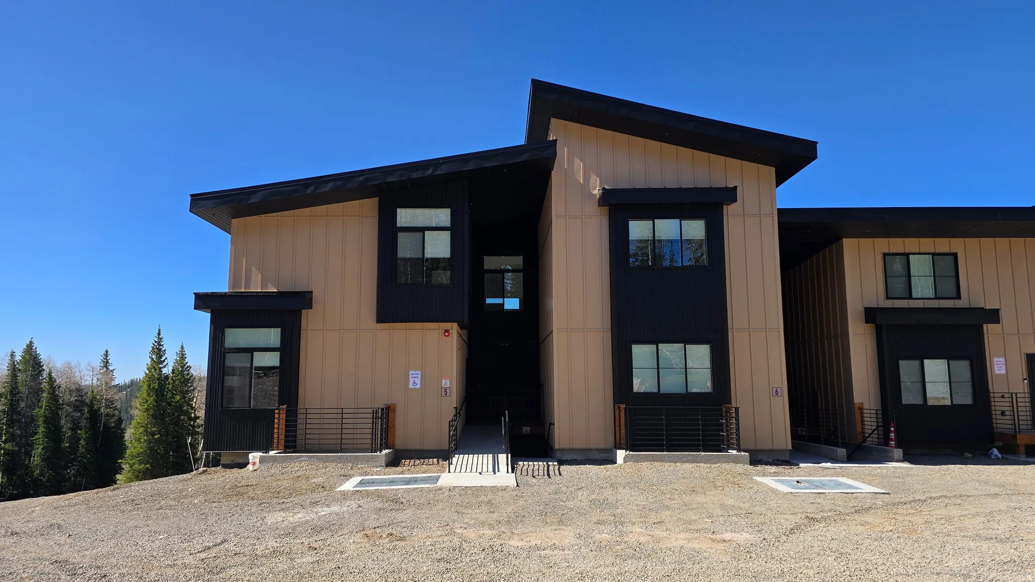 Modern multi-story building featuring a contrasting façade of light-colored vertical siding and dark-paneled sections