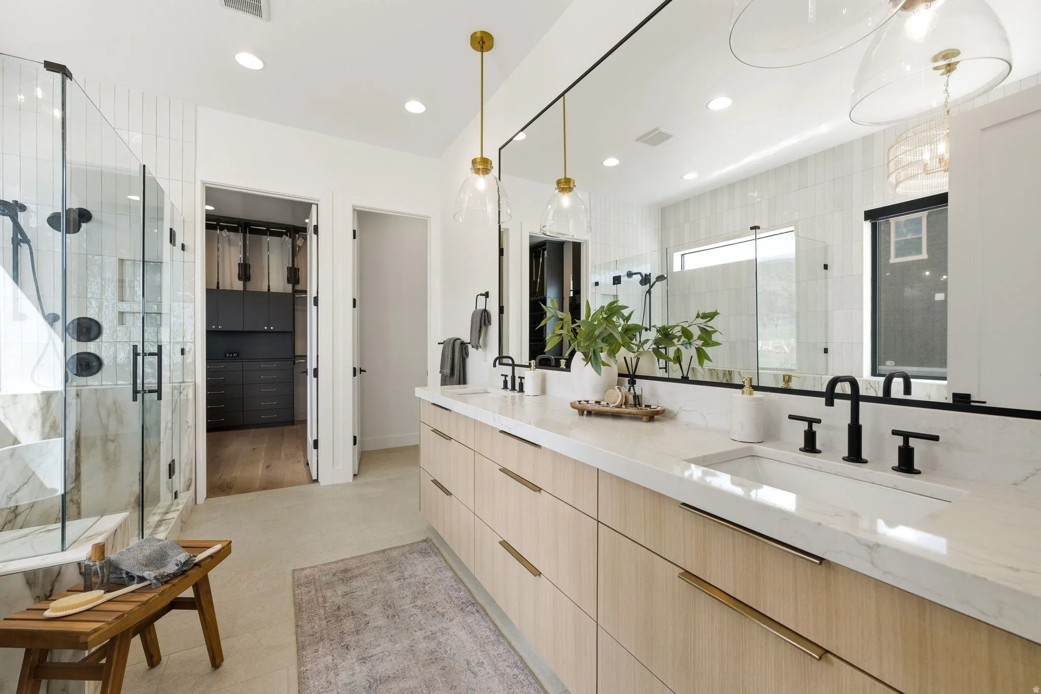Dual vanity featuring wood-finish cabinetry, white countertops, and matte black fixtures