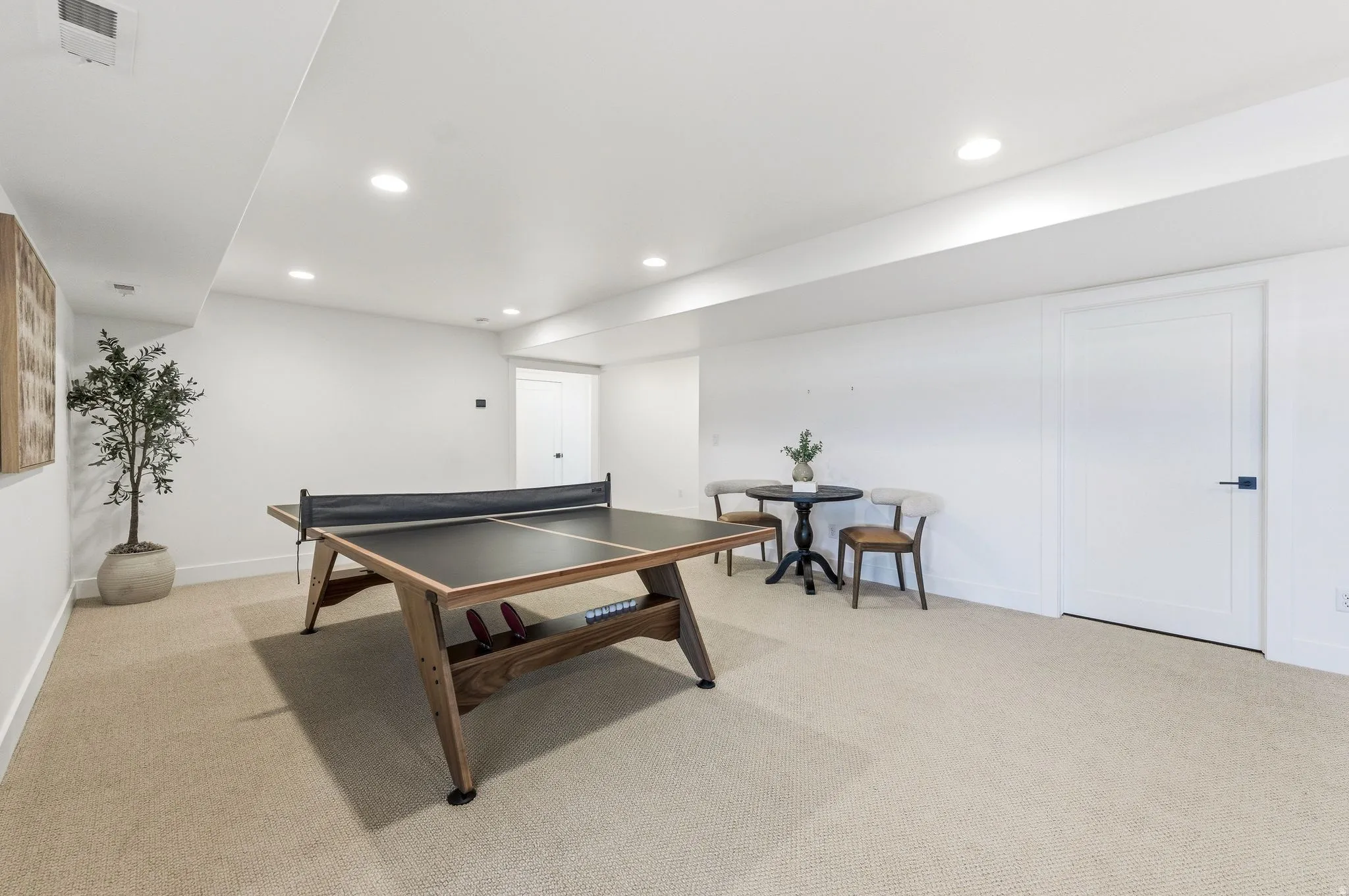 Spacious room featuring neutral carpeting, recessed lighting, white walls, and a built-in ceiling soffit