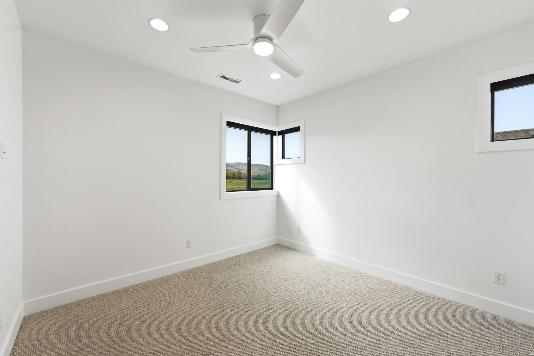 Bright room featuring a ceiling fan, recessed lighting, and expansive windows