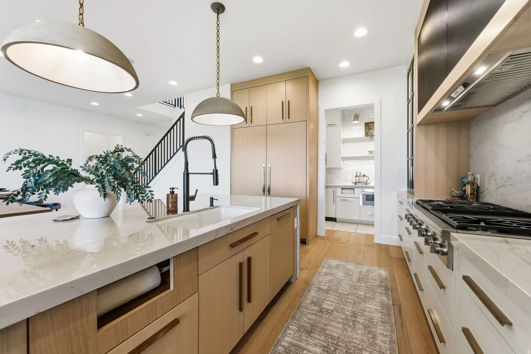 Contemporary kitchen featuring a large island with an undermount sink and a matte black faucet