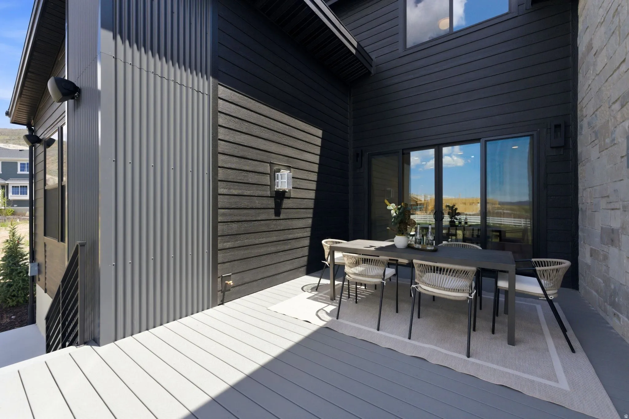 Upper-level deck featuring composite decking, dark wood-finish siding, and a sliding glass door