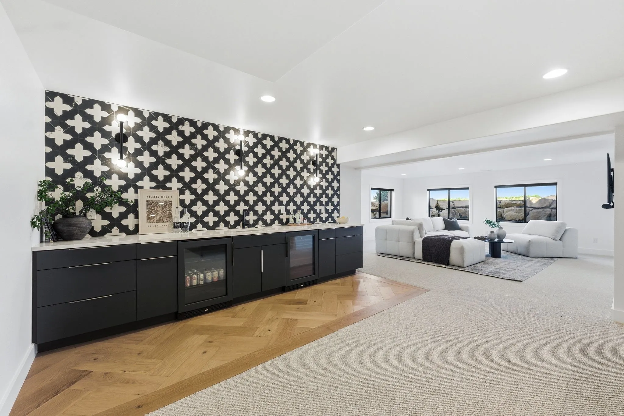 Open-concept entertainment space featuring a patterned tile accent wall, built-in cabinetry with integrated beverage coolers, and warm wood-finish flooring