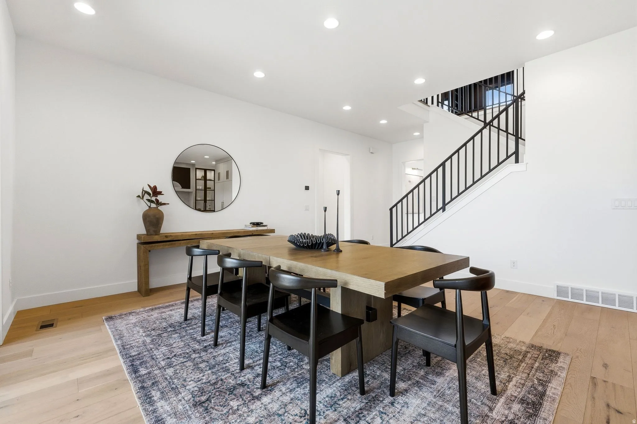 Bright dining area featuring light wood-finish flooring, recessed lighting, and white walls