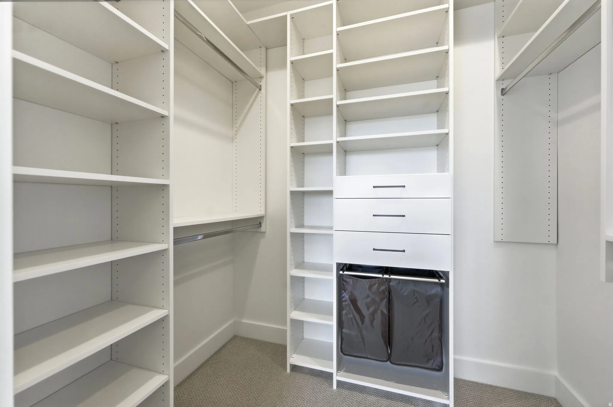 Custom closet system featuring multiple shelving units, hanging rods, and integrated drawers with dark hardware