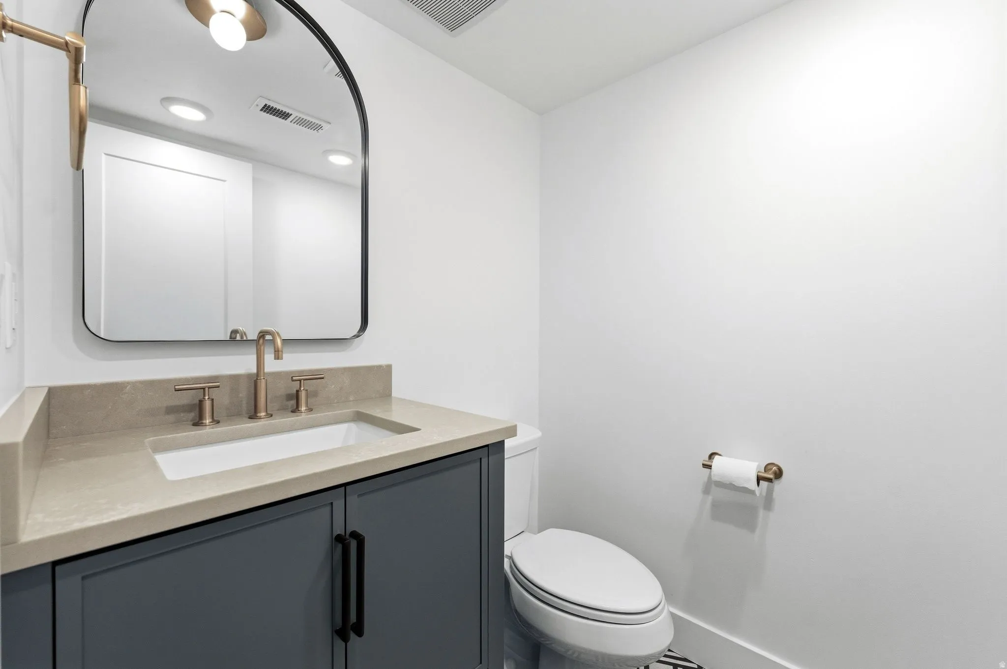 Contemporary vanity with a rectangular undermount sink, light-toned countertop, and gold-finish faucet