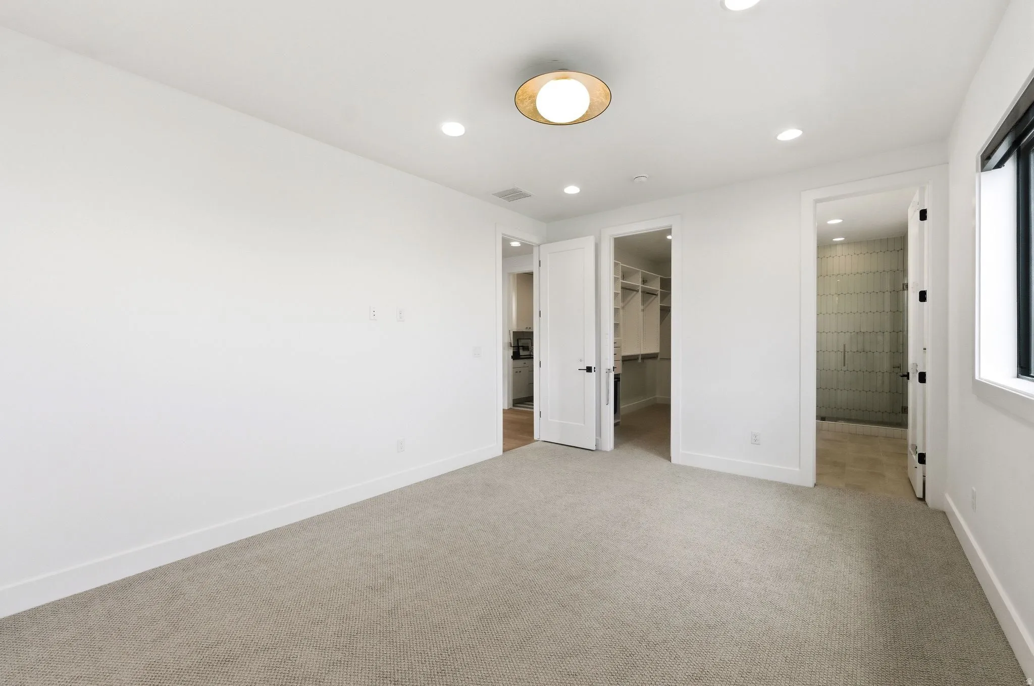 Carpeted room with white walls, a modern circular ceiling light fixture, recessed lighting, and a dark-framed window