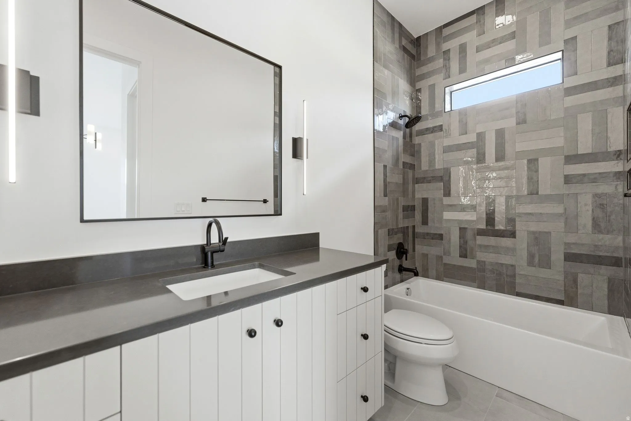 Bathroom featuring a white vanity with paneling, dark countertop, and matte black fixtures