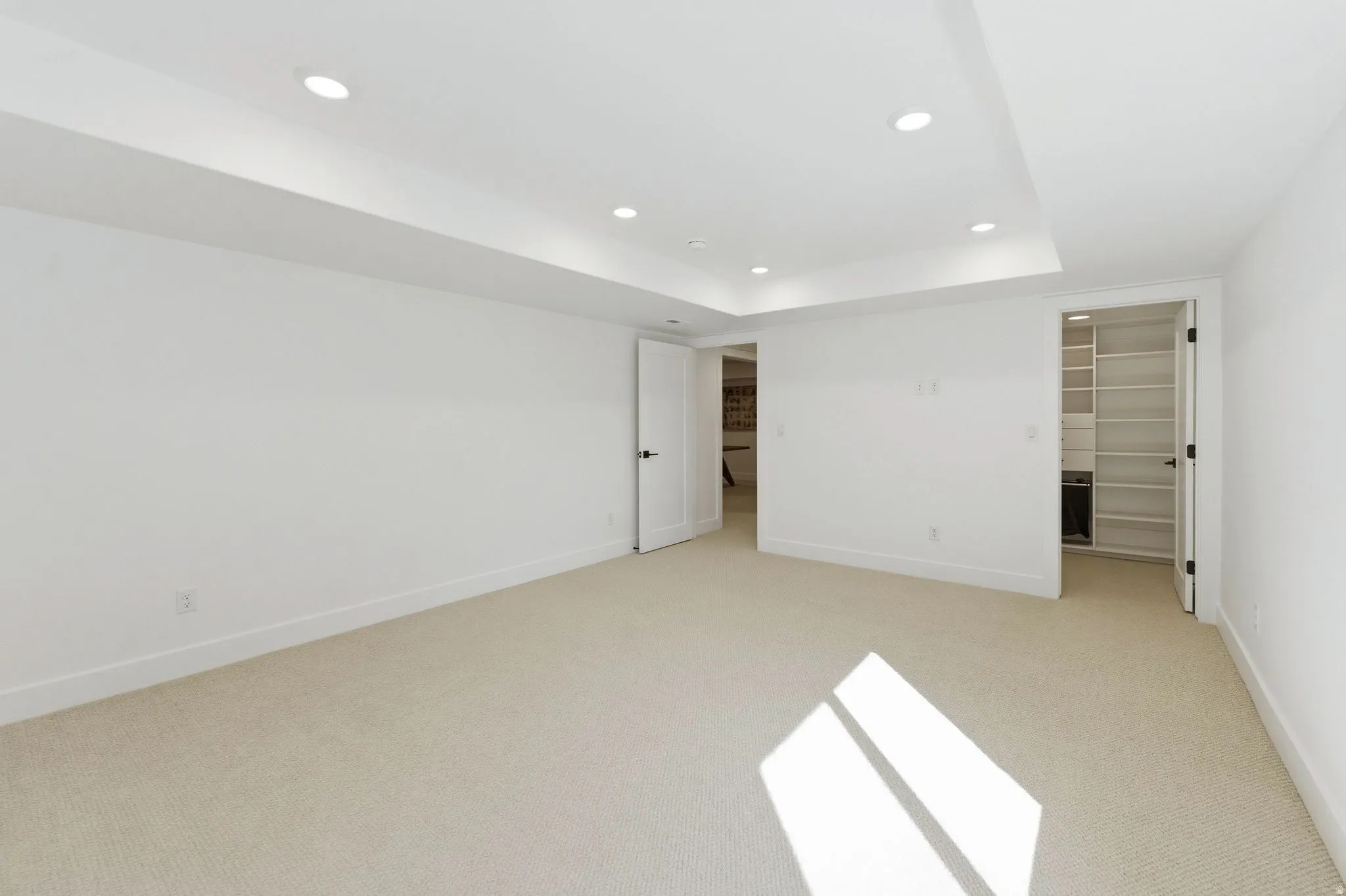 Spacious room with light-toned carpeting and white walls