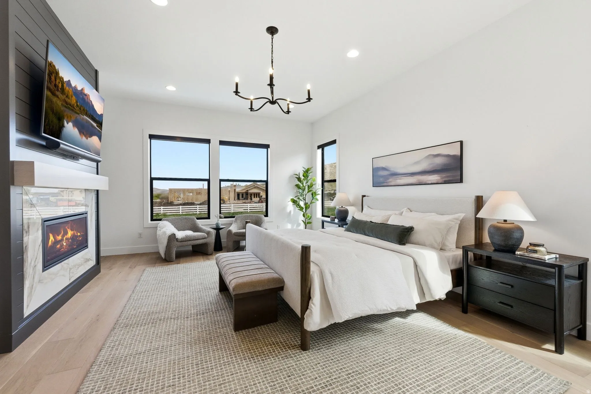 Bedroom featuring a built-in fireplace with a tiled surround, wood-finish flooring, a contemporary chandelier, recessed lighting, and multiple windows