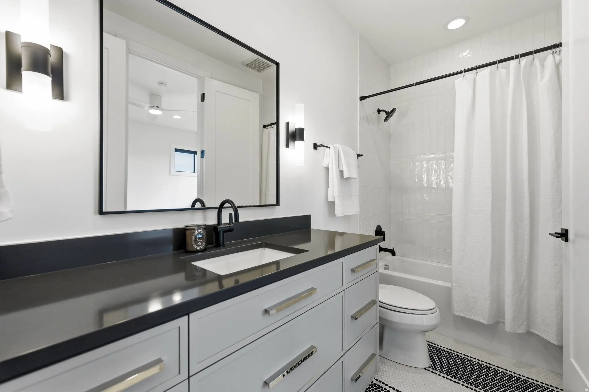 Bathroom featuring a dark countertop vanity with white cabinetry, a rectangular undermount sink, and matte black fixtures
