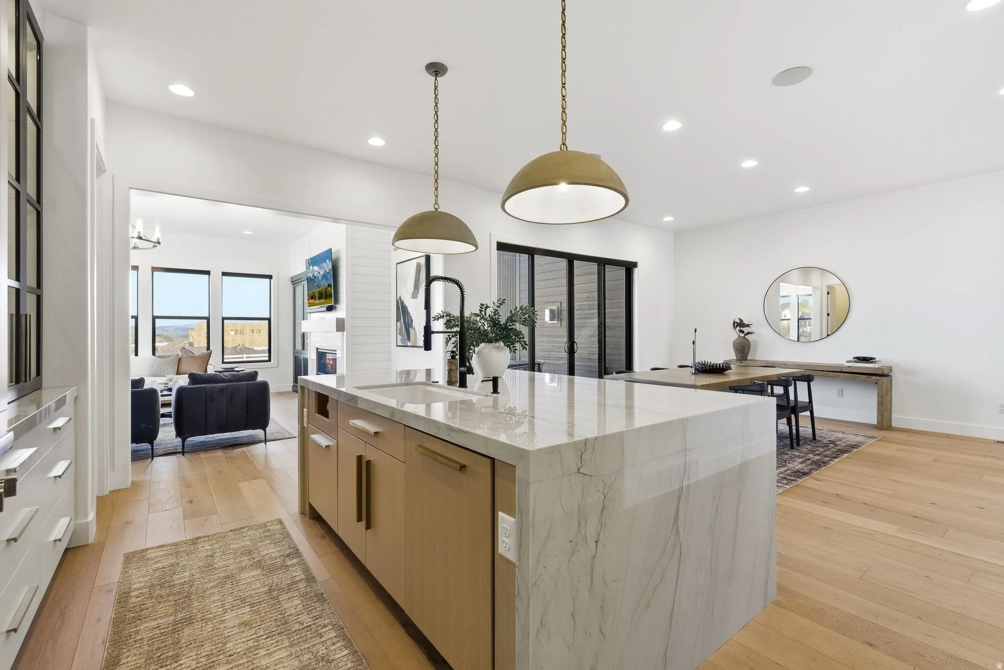 Gourmet kitchen island with waterfall countertop, integrated sink, and dual pendant lighting