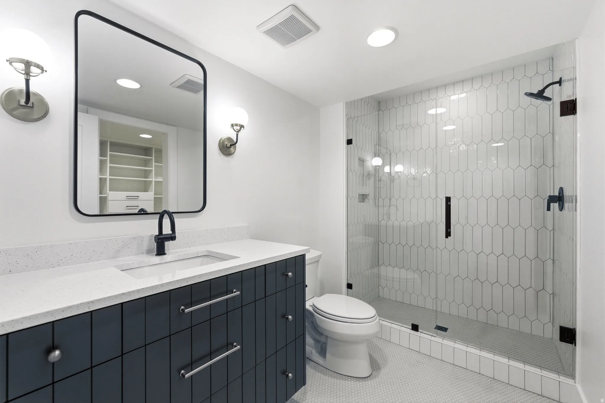Contemporary bathroom featuring a dark blue vanity with a white countertop, an undermount sink, and a black framed mirror